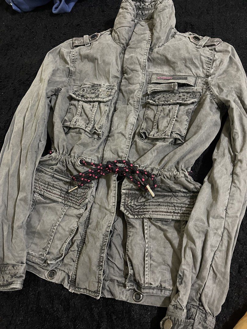 Superdry Limited Edition Flag Jacket Military Issue (Category: Coats, Jackets and Outerwear) located in La Trinidad. Submitted by potatothriftlip (Listing ID 1468057806, Image 1). Description: - Brand: Superdry - Style: Military Issue Limited Edition Flag Jacket - Color/Wash: Grey - Details: Mandarin regimental collar with snap buttons, metal hardware - Pockets: Multiple utility pockets for functionality - Waist: Adjustable drawstring with black 