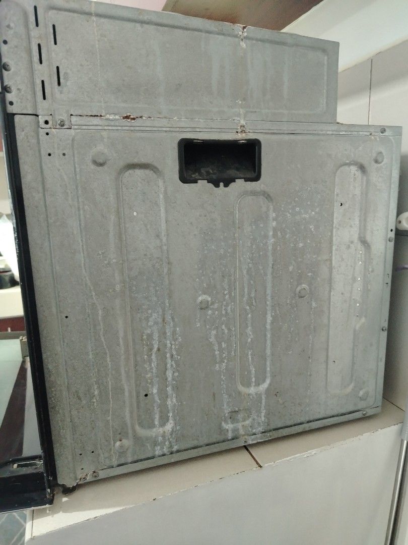 Tekno Built-in Oven Stainless Steel (Category: Ovens & Toasters) located in Makati City. Submitted by mercianalech (Listing ID 1468059054, Image 3). Description: - Type: Stainless steel built-in kitchen oven - Controls: Three knobs on the top panel - Door: Drop-down glass door - Interior: Includes racks, metal baking trays, and a back wall fan vent - Condition: Outer metal housing shows wear, water marks, and minor rust along the edges.