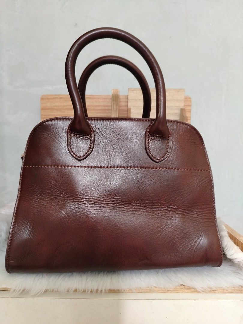 The Row Margaux 10 (Category: Tote Bags) located in Lucena. Submitted by gracious_chin0436 (Listing ID 1467841349, Image 1). Description: - Brand: The Row - Color: Rich brown - Material: Premium pebbled leather with clean stitching - Hardware: Gold-tone side buckle and logo stamp - Design: Structured shape with dual top handles - Protection: Four metal feet on the bottom base - Handbag only missing long strap for crossbody -with normal to minimal