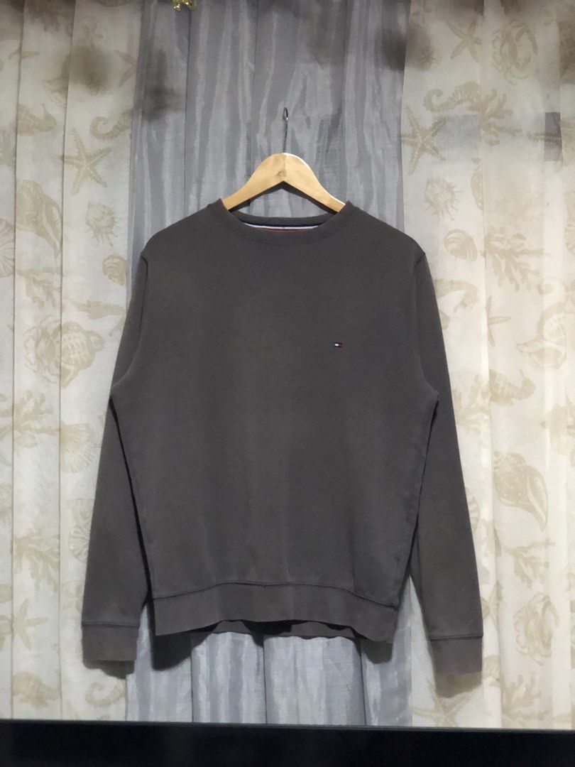 Tommy Hilfiger Grey Sweatshirt (Category: Coats, Jackets and Outerwear) located in Calbayog City. Submitted by thriftme.bro (Listing ID 1468008646, Image 1). Description: Classic dark grey sweatshirt from Tommy Hilfiger. Long sleeves with ribbed cuffs and hem. Small embroidered logo patch on the left chest. Striped taping along the inner collar. Fabric blend is 72% cotton and 28% polyester. Made in Sri Lanka. Clean and simple design for everyday 