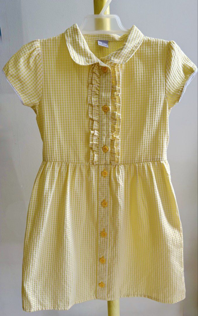 Tu School Yellow Gingham Dress (Category: Babies & Kids Fashion) located in Quezon City. Submitted by warmrabbit_414908 (Listing ID 1467876833, Image 1). Description: - Brand: Tu School - Color/Pattern: Bright yellow gingham - Material: Lightweight cotton with lining - Details: Classic collar, ruffled front placket, front buttons - Sleeves: Short cap sleeves with delicate lace trim - Fit: Attached waist tie belt in the back - Condition: Clean and