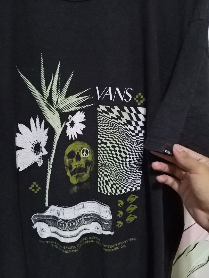 Vans Off the Wall Graphic Tee 2XL (Category: Tshirts & Polo Shirts ) located in Magdalena. Submitted by magdalenathrift20 (Listing ID 1467984613, Image 3). Description: - Brand: Vans - Style: Classic fit graphic t-shirt - Color: Black - Design: Bold front graphic with flowers, skull, and checkerboard pattern - Details: Small logo tag on left sleeve cuff - Material: 100% cotton - Size: XX-Large - Measurements (laid flat): Width 26.5 inches, Length