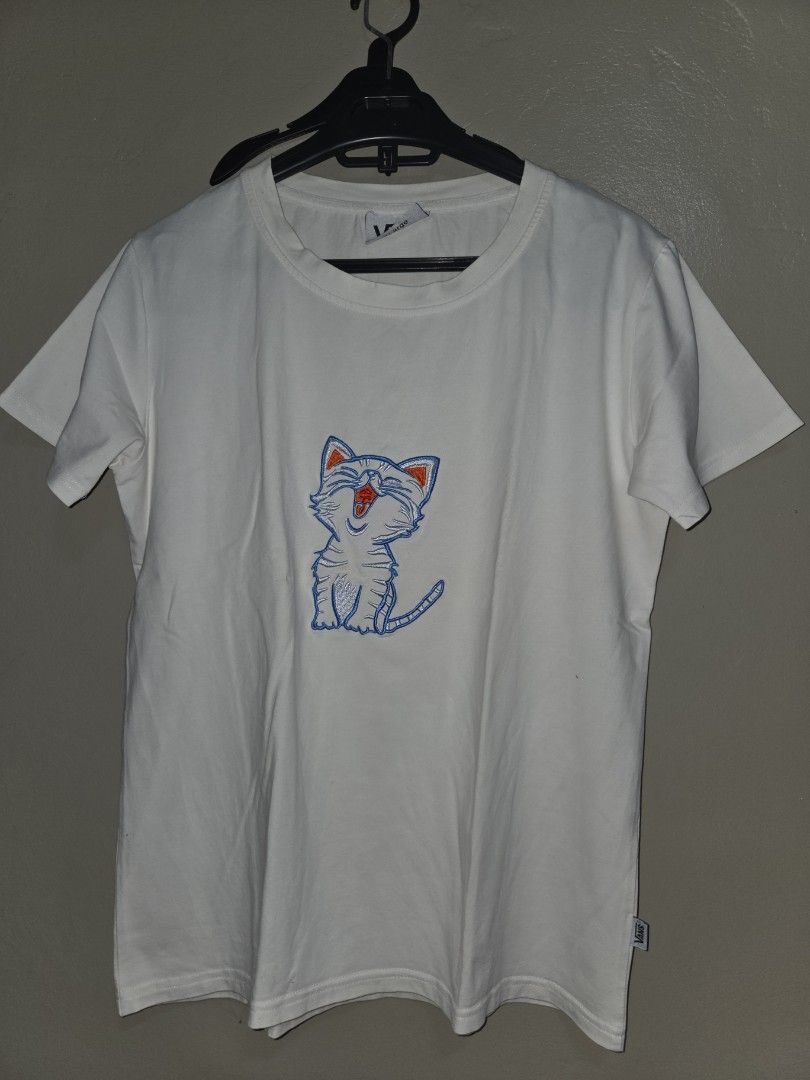 Vans White T-Shirt with Embroidered Cat Graphic (Category: Shirts) located in Quezon City. Submitted by klarebear15 (Listing ID 1468024600, Image 1). Description: - Brand: Vans - Color: White - Material: Soft, comfortable cotton - Design: Center chest embroidered cat graphic with blue outlines and orange ears - Details: Small woven Vans logo tab on the right hem - Fit/Style: Classic crew neck, standard hem, great casual streetwear basic - Conditi