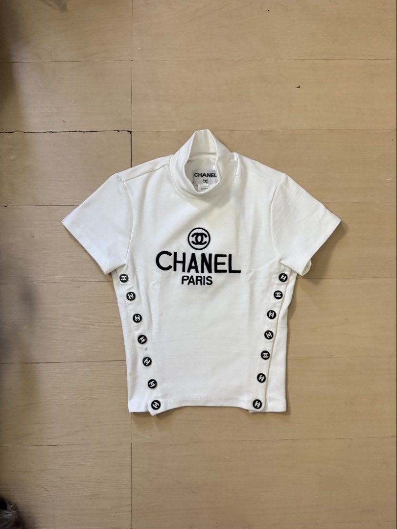 Vintage Chanel Top (Category: Shirts) located in Manila. Submitted by juhjuh (Listing ID 1467914046, Image 1). Description: - Authentic Chanel short sleeve top in crisp white S/M - Chic mock neckline with branded inner neck label - Bold black 'Chanel Paris' logo and CC symbol on the chest - Unique decorative black and white CC buttons along both side seams - Flattering, fitted cut with a clean fabric finish - Condition: Excellent / Like new.