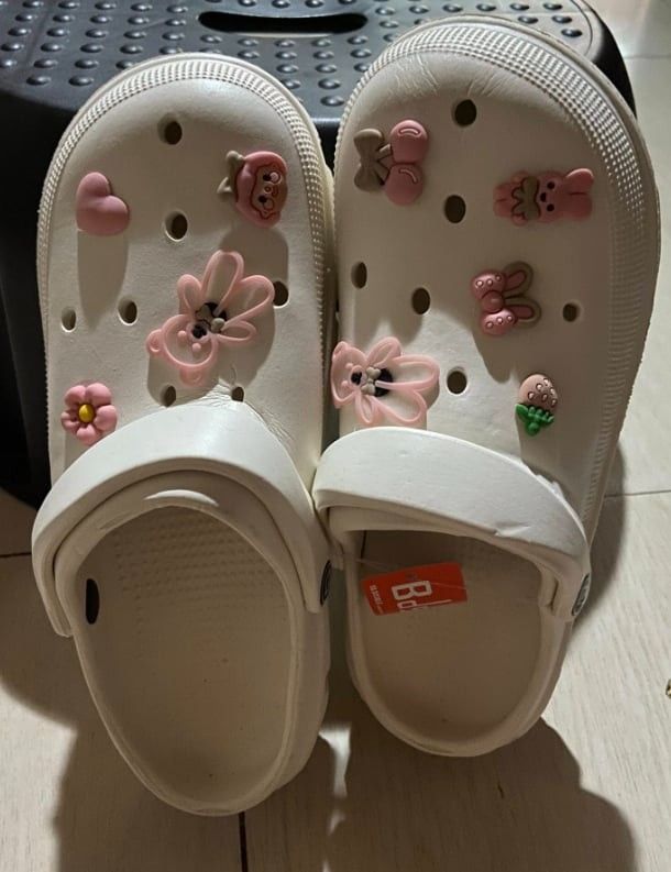 White Clogs with Cute Pink Charms (Category: Slippers and slides) located in Zaragoza. Submitted by sherree1281 (Listing ID 1468058858, Image 1). Description: - Condition: Brand new with original store tag on inner sole - Design: Cute white slip-on clogs with pink charms (flowers, bears, and strawberries) - Comfort: Features a supportive chunky heel strap for all-day wear - Style: Fun, playful, and ready to wear.