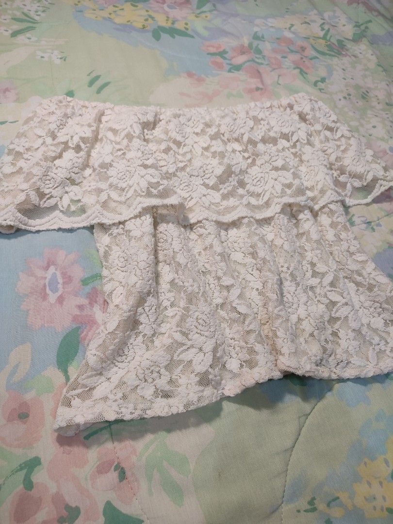 White lace off-shoulder layered ruffle top (Category: Blouses) located in Jaen. Submitted by roxantiago (Listing ID 1468038350, Image 2). Description: - Color: Cream white - Material: Full floral lace (sheer, inner lining needed) - Design: Off-shoulder with a layered ruffle overlay at the chest - Fit: Stretchy elastic neckline for a secure fit - Styling: Great for pairing with denim shorts or skirts.