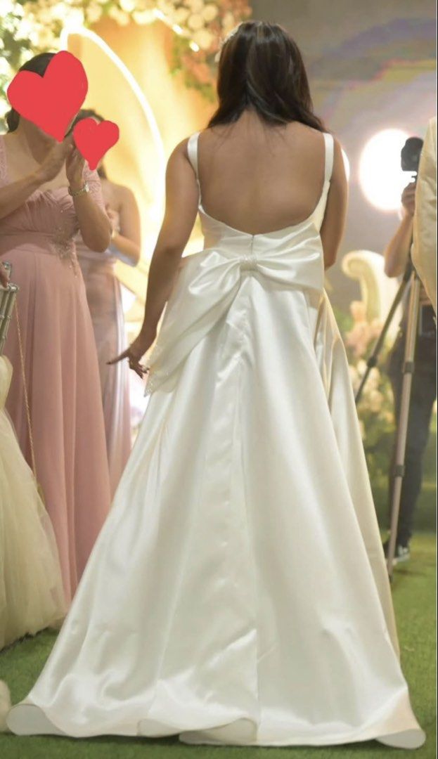 White satin wedding gown with back bow (Category: Evening dresses & gowns) located in Manila. Submitted by nicadelacr28495 (Listing ID 1467883849, Image 1). Description: - Color: Classic White - Material: Smooth satin finish - Design: Scoop neckline with supportive thick straps and a chic low back - Statement Detail: Large bow at the lower back - Silhouette: Flattering flowing A-line skirt with a subtle train.