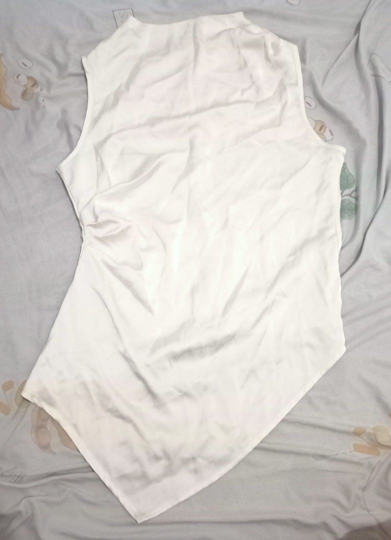 White sleeveless asymmetric hem blouse top (Category: Sleeveless) located in Makati City. Submitted by gonzalesde66090 (Listing ID 1467969661, Image 1). Description: - Color: cream color may vary due to lightning - Style: Sleeveless top with mock neck and clean minimal look - Design: Asymmetric handkerchief hem with sharp, elongated front and back points - Closure: Easy-wear back zipper - Fabric: Lightweight and smooth silky material - Versatilit