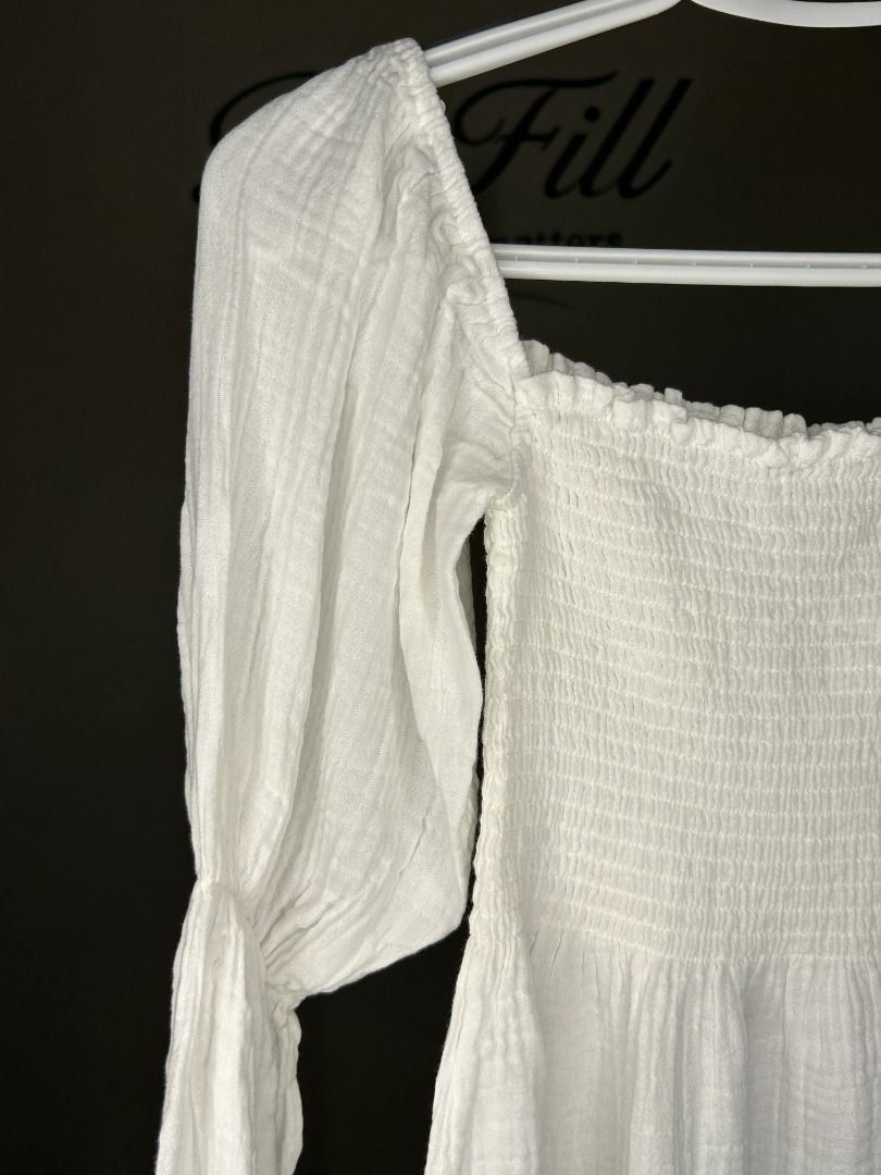 White Square Neck Long Sleeve Dress (Category: Dresses) located in Taguig. Submitted by re.wear.mnl (Listing ID 1468008355, Image 2). Description: - Color: White - Style: Mini dress with square neckline and flowy skirt - Details: Long sleeves with ruffled cuffs, heavily smocked bodice, and textured crinkle finish - Material: Lightweight cotton gauze (pullover style) - Versatility: Great for casual days out, weekend brunches; pairs well with flats