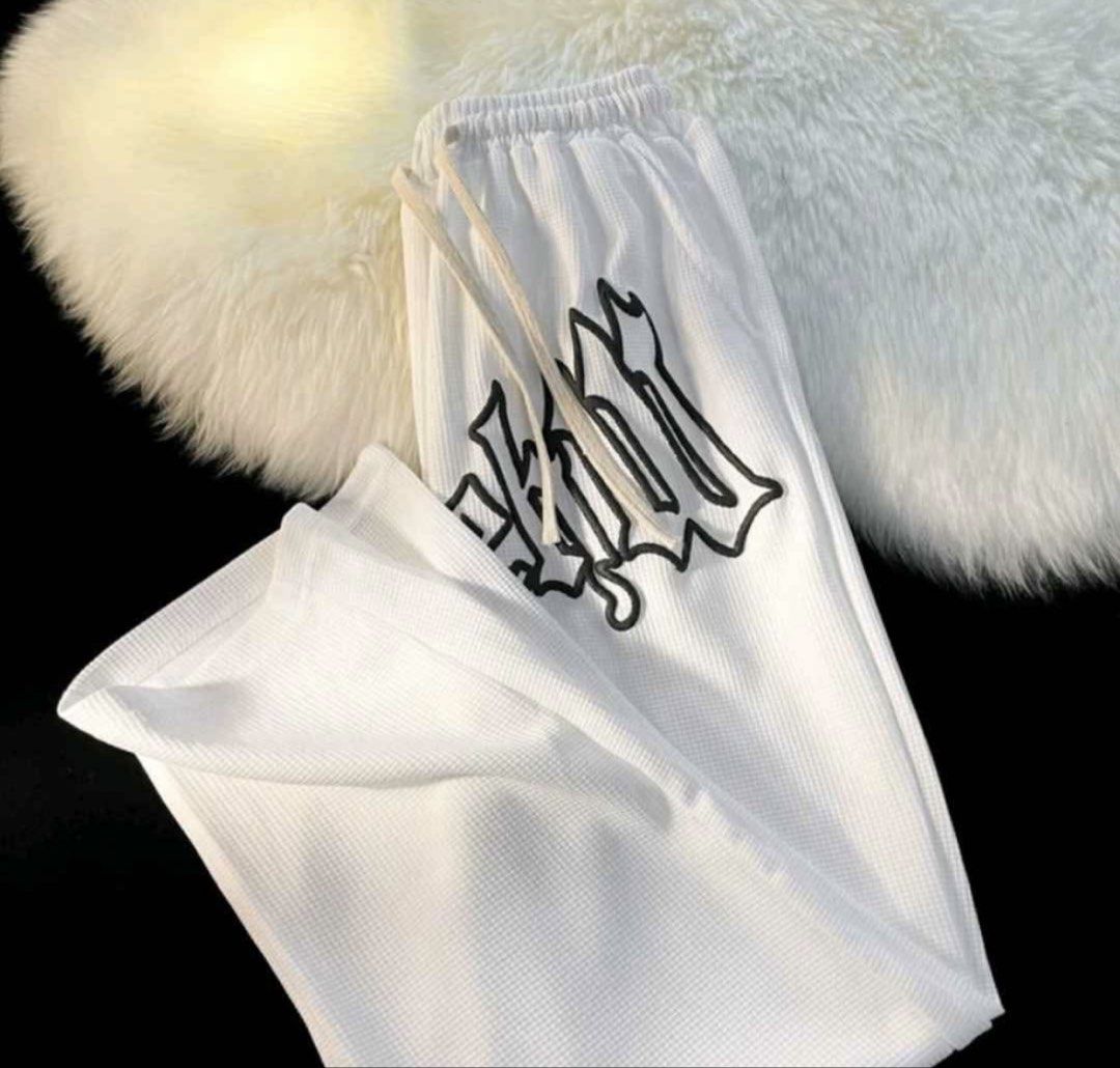 White Waffle Knit Graphic Joggers Sweatpants (Category: Joggers) located in Baras. Submitted by vale831 (Listing ID 1468030731, Image 1). Description: - Color: White with black gothic lettering down the leg - Material: Lightweight textured waffle knit, super comfortable - Fit: Relaxed fit with a trendy wide-leg style - Waistband: Elastic with adjustable drawstrings - Style: Perfect for daily wear, lounging, or streetwear looks.