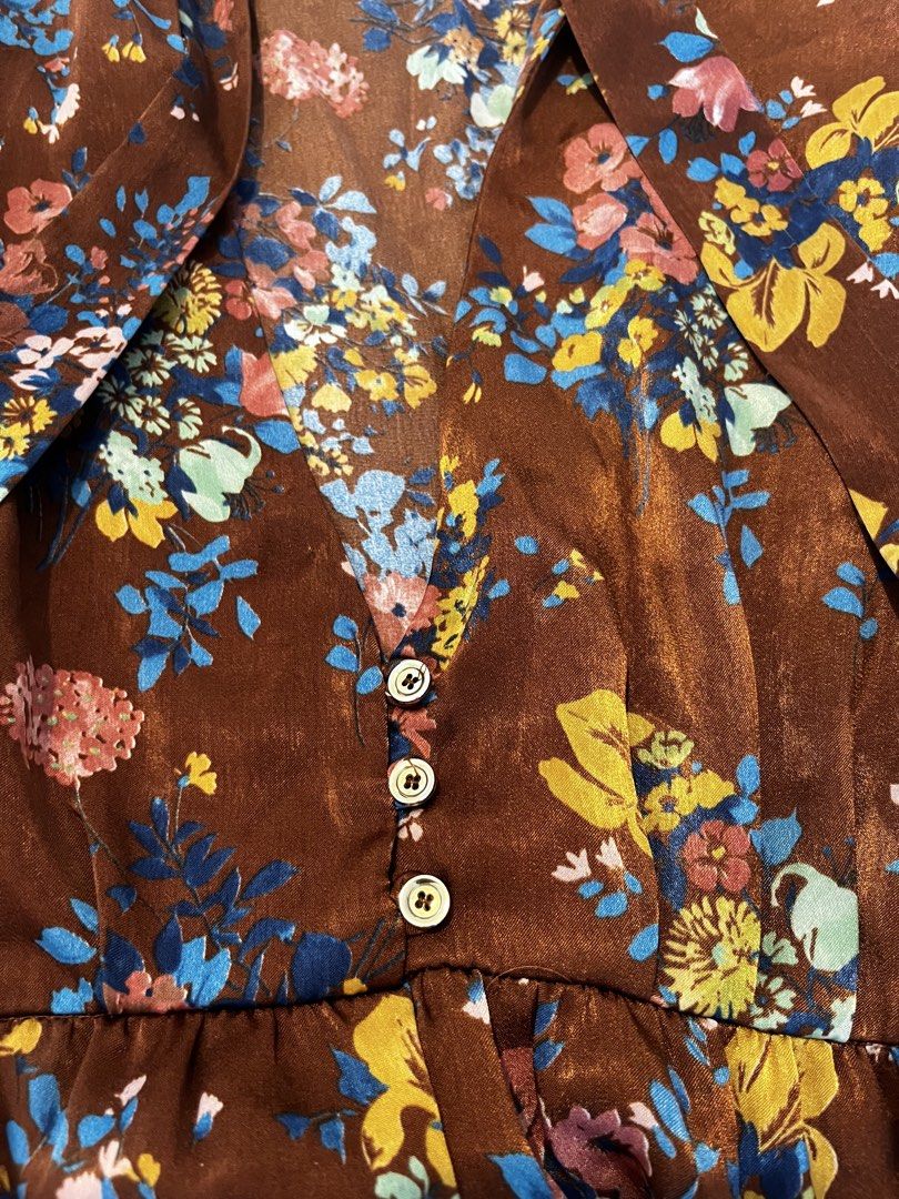 Zara Basic Floral Brown Long Sleeve Dress (Category: Dresses) located in Manila. Submitted by lorenasant37621 (Listing ID 1467900799, Image 3). Description: - Brand: Zara Basic - Style: Midi dress with relaxed skirt and fitted waist - Color/Pattern: Brown with vibrant blue, yellow, and pink floral print - Details: High neckline with self-tie bow ribbon, partial front button placket, long sleeves with buttoned cuffs (1 button missing) - Material: 