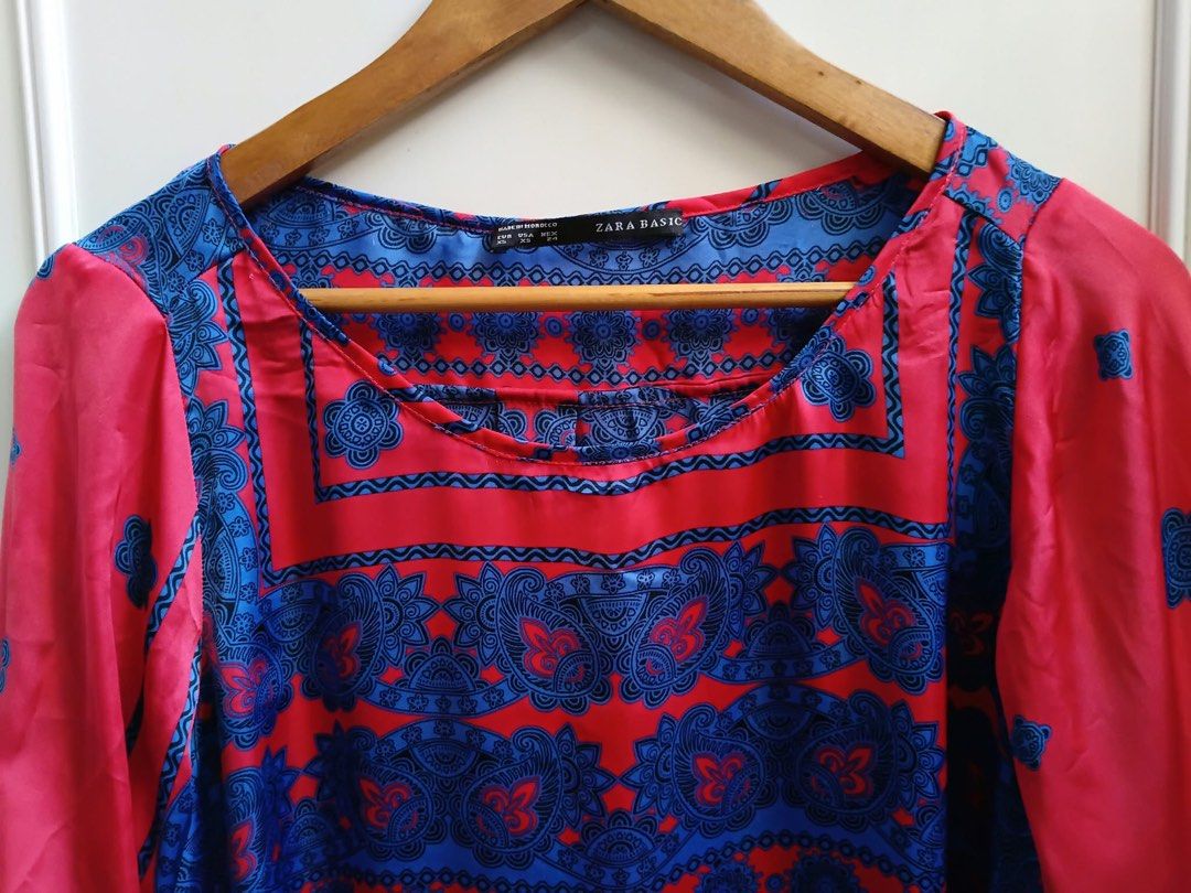 Zara Basic Red and Blue Patterned Blouse Size XS ( 19x25/28) (Category: Blouses) located in Calapan. Submitted by shakalak (Listing ID 1467893206, Image 3). Description: - Brand: Zara Basic( Made in Morocco) - Size: XS -Medium - Color/Pattern: Bright red and blue with intricate paisley and geometric prints - Neckline: Scoop neck - Sleeves: Three-quarter sleeves with roll-tab button details - Hem: High-low curved hem - Material: Lightweight silky 