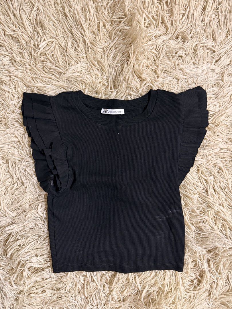 Zara Black Ribbed Ruffle Sleeve Top (Category: Sleeveless) located in Manila. Submitted by theaxxxx (Listing ID 1467890121, Image 1). Description: - Brand: Zara - Color: Black - Size: S - Material: Stretchy cotton blend ribbed fabric - Design: Round neckline, short flutter ruffle sleeves, cropped fit - Condition: Worn a few times, solid shape - Style: Easy to match with jeans or skirts for casual looks.