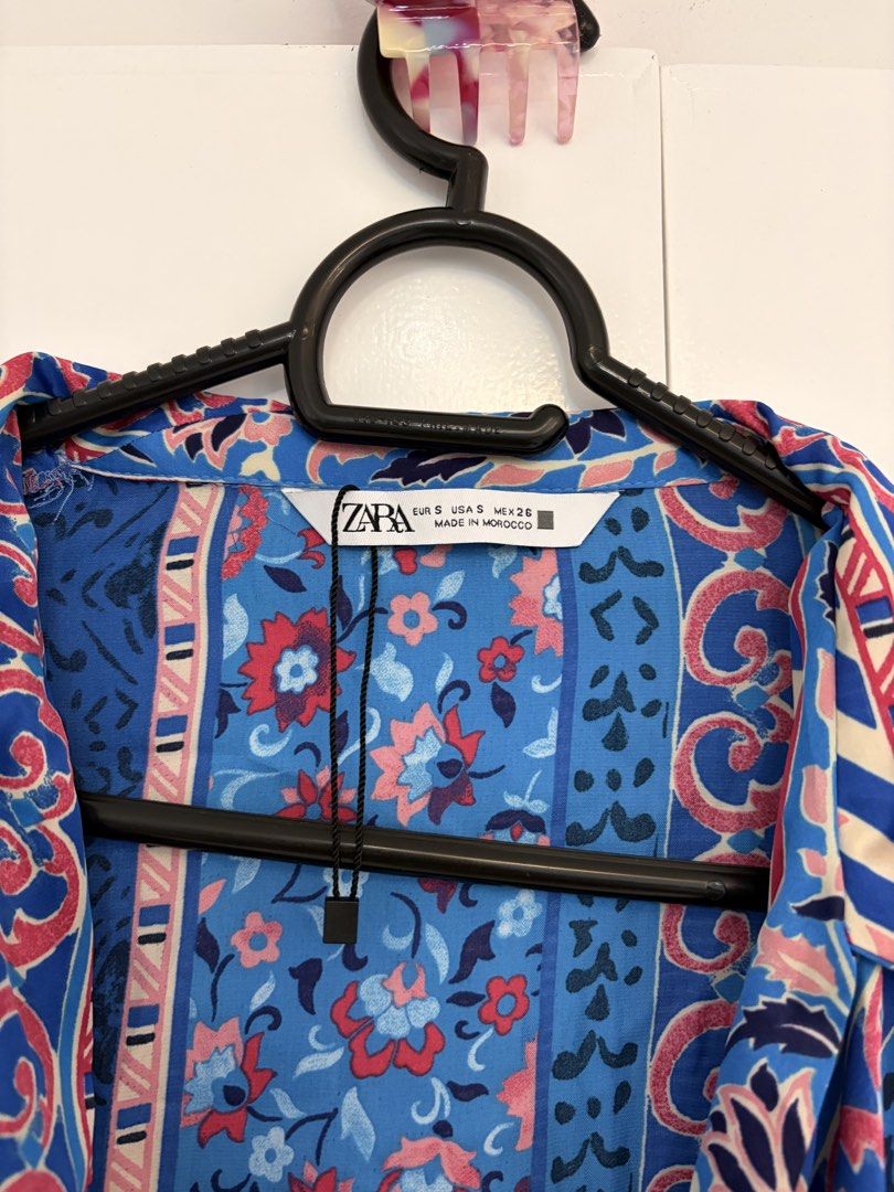 Zara Blue Floral Wrap Blouse Size S (Category: Blouses) located in Quezon City. Submitted by prelovedbynxkole (Listing ID 1467884704, Image 2). Description: - Brand: Zara - Size: S (Made in Morocco) - Condition: Brand new, but lost tag haha - Color/Pattern: Blue with pink floral and geometric prints - Style: Wrap front design, lapel collar, and long bell sleeves - Perfect for: Casual days out, easily styled with high-waisted pants or skirts ALL C