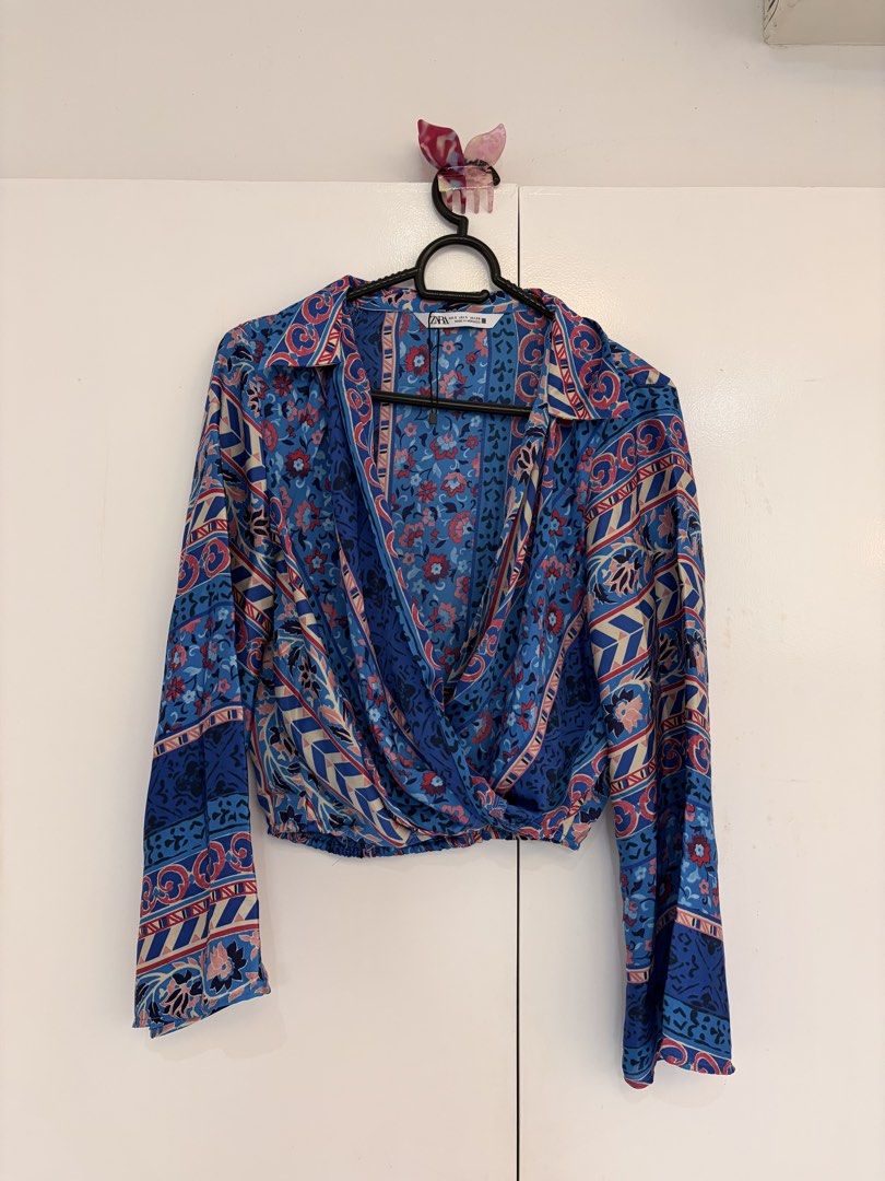 Zara Blue Floral Wrap Blouse Size S (Category: Blouses) located in Quezon City. Submitted by prelovedbynxkole (Listing ID 1467884704, Image 1). Description: - Brand: Zara - Size: S (Made in Morocco) - Condition: Brand new, but lost tag haha - Color/Pattern: Blue with pink floral and geometric prints - Style: Wrap front design, lapel collar, and long bell sleeves - Perfect for: Casual days out, easily styled with high-waisted pants or skirts ALL C