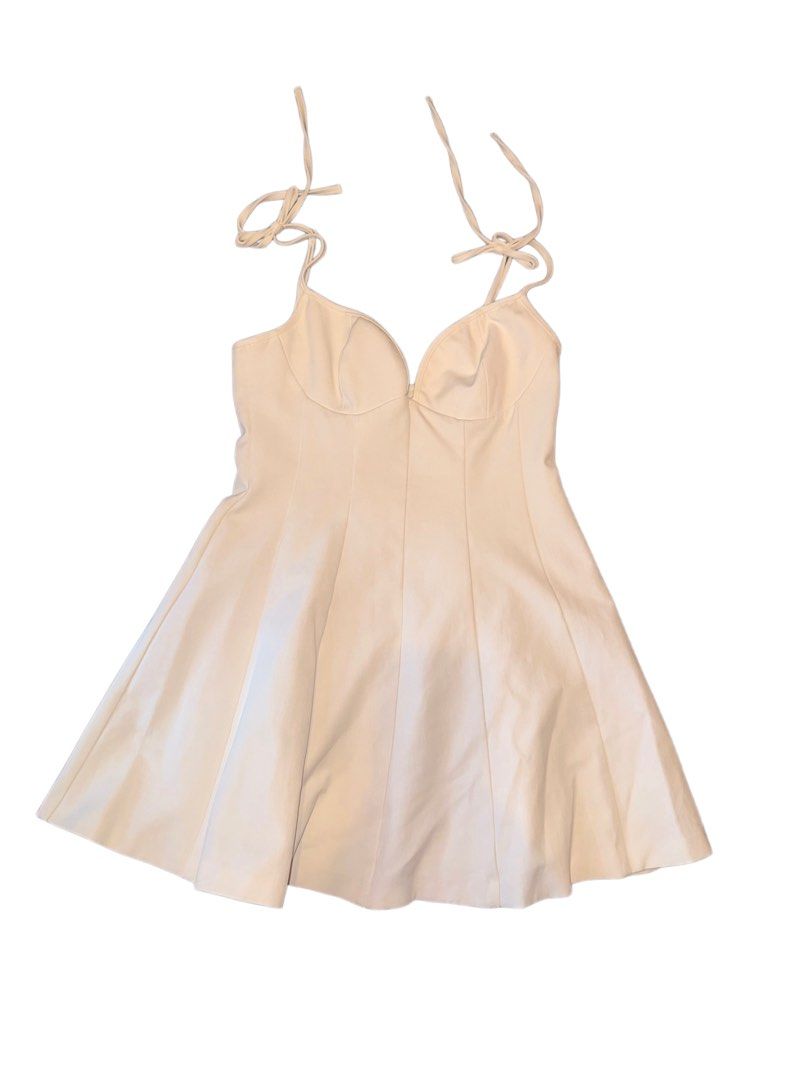 Zara Dress (Category: Dresses) located in Manila. Submitted by ilove.sushi (Listing ID 1467919176, Image 1). Description: - Color: Cream beige - Style: Skater dress with a flared mini skirt - Bodice: Fitted bustier with panel details - Straps: Adjustable tie-straps at the shoulders - Material: Smooth and structured fabric - Versatility: Easy to dress up or down for any occasion.
