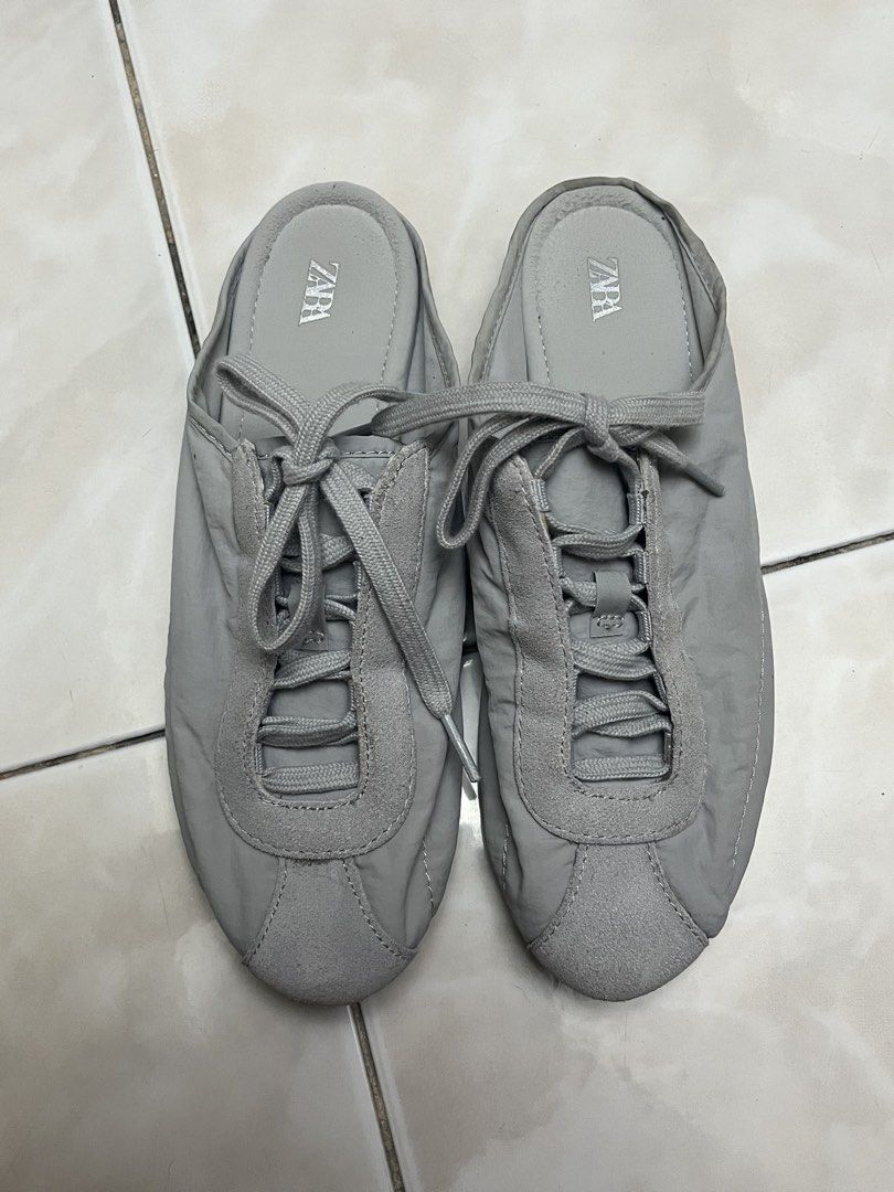 Zara Grey Slip-On Sneaker Mules (Category: Flats & Sandals) located in Quezon City. Submitted by sunday.closet (Listing ID 1467942822, Image 1). Description: - SIZE 36 - Style: Grey slip-on mules - Details: Puffer-style upper with lace detailing and suede-like toe cap - Sole: Rubber pebble sole with embossed Zara logo at the heel - Condition: Decent shape, clean insoles, and minor dirt marks on the bottom soles from normal wear - Perfect for: Eas