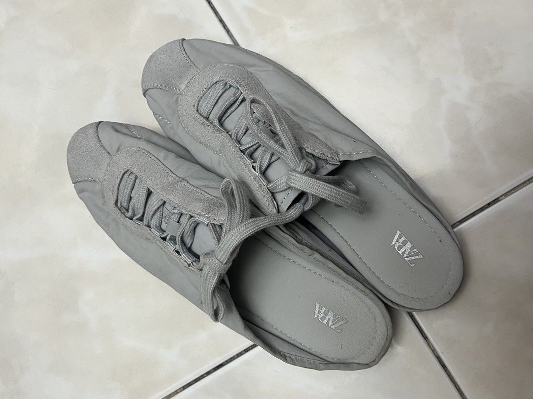 Zara Grey Slip-On Sneaker Mules (Category: Flats & Sandals) located in Quezon City. Submitted by sunday.closet (Listing ID 1467942822, Image 2). Description: - SIZE 36 - Style: Grey slip-on mules - Details: Puffer-style upper with lace detailing and suede-like toe cap - Sole: Rubber pebble sole with embossed Zara logo at the heel - Condition: Decent shape, clean insoles, and minor dirt marks on the bottom soles from normal wear - Perfect for: Eas