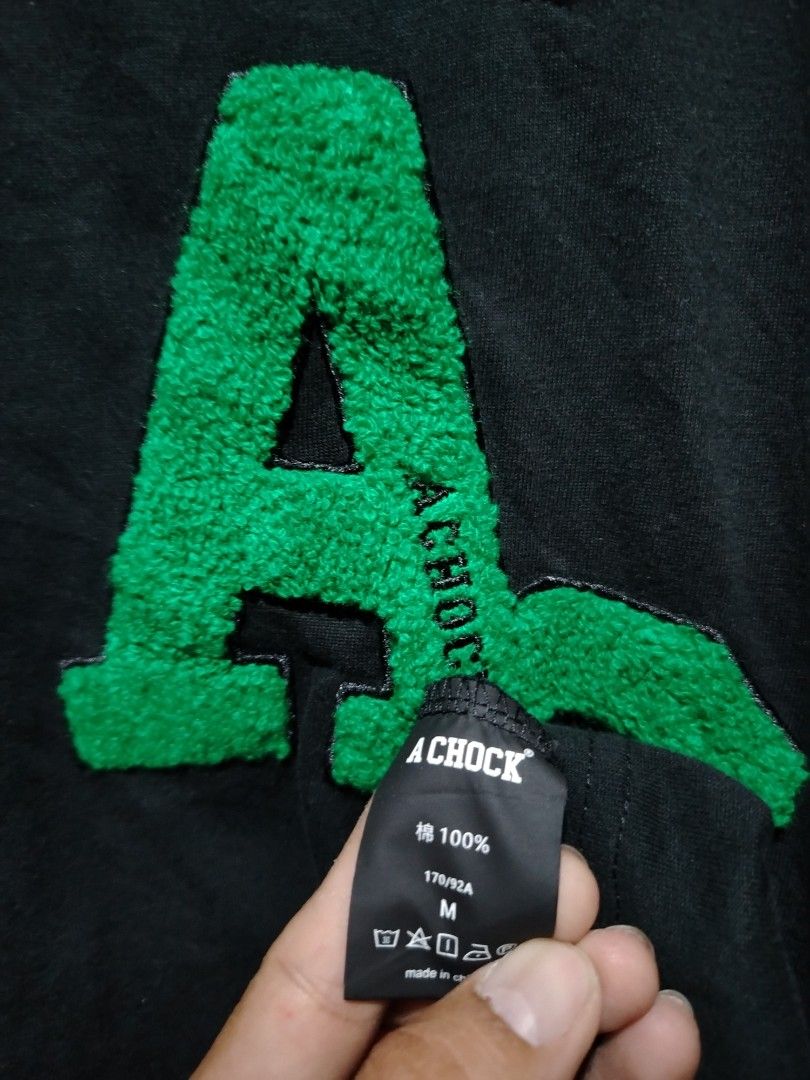 A Chock Black Long Sleeve Shirt Green Patch Size M (Category: Longsleeves) located in Caloocan City. Submitted by vincefresn21903 (Listing ID 1468282014, Image 3). Description: - Brand: Chock - Color: Black - Size: M (170/92A) - Material: 100% Cotton - Design: Big green textured AC patch on front chest - Feature: Zipper detail near the left collar - Details: Crew neck with ribbed cuffs and hem - Condition: Clean overall condition.
