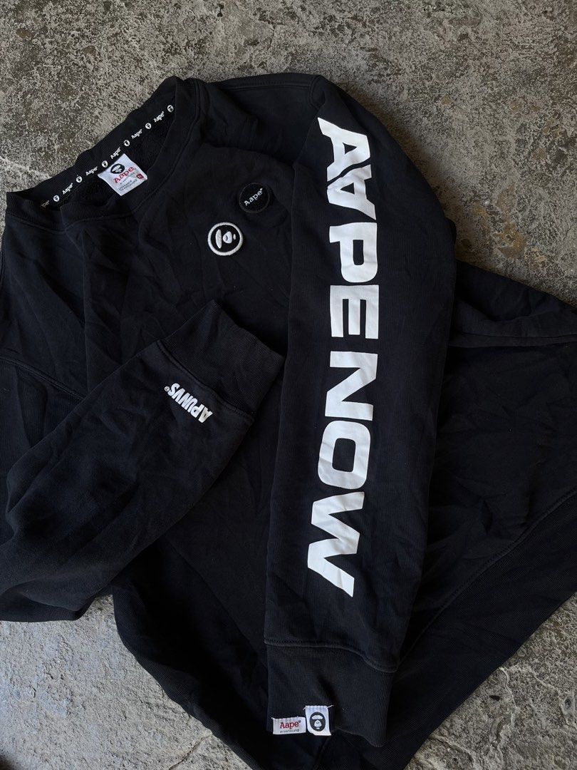 AAPE by A Bathing Ape Black Sweatshirt XL (Category: Coats, Jackets and Outerwear) located in Aguilar. Submitted by brad11thrift (Listing ID 1468186562, Image 3). Description: Black sweatshirt from AAPE by A Bathing Ape. Bold 'AAPE NOW' lettering printed down the left sleeve. Small white and black brand patches on the chest and lower sleeve hem. Inside collar tape repeats the brand name all around. Ribbed cuffs and hem. Size XL on the inner tag..