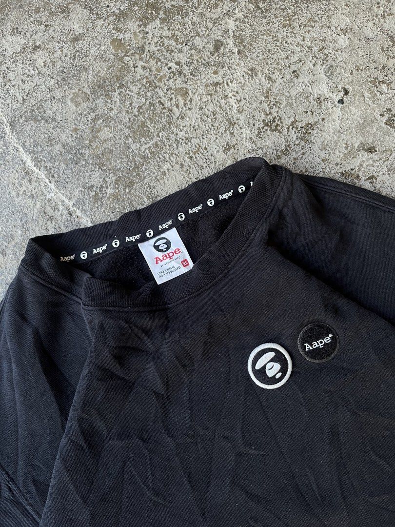AAPE by A Bathing Ape Black Sweatshirt XL (Category: Coats, Jackets and Outerwear) located in Aguilar. Submitted by brad11thrift (Listing ID 1468186562, Image 2). Description: Black sweatshirt from AAPE by A Bathing Ape. Bold 'AAPE NOW' lettering printed down the left sleeve. Small white and black brand patches on the chest and lower sleeve hem. Inside collar tape repeats the brand name all around. Ribbed cuffs and hem. Size XL on the inner tag..
