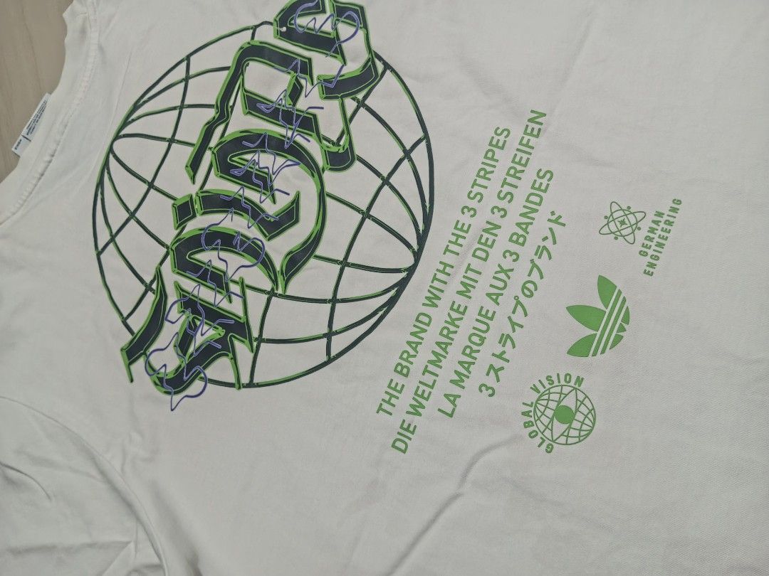 Adidas White Graphic Tee Size S (Category: Tshirts & Polo Shirts ) located in Manila. Submitted by charleshustla (Listing ID 1468195467, Image 3). Description: - Brand: Adidas - Size: Small (S) - Color: Clean White - Design Front: Vertical gothic lettering with iconic trefoil logo - Design Back: Large globe graphic with multilingual text and German Engineering stamp - Fit: Short sleeves, classic crew neck - Condition: Excellent, ready to wear.