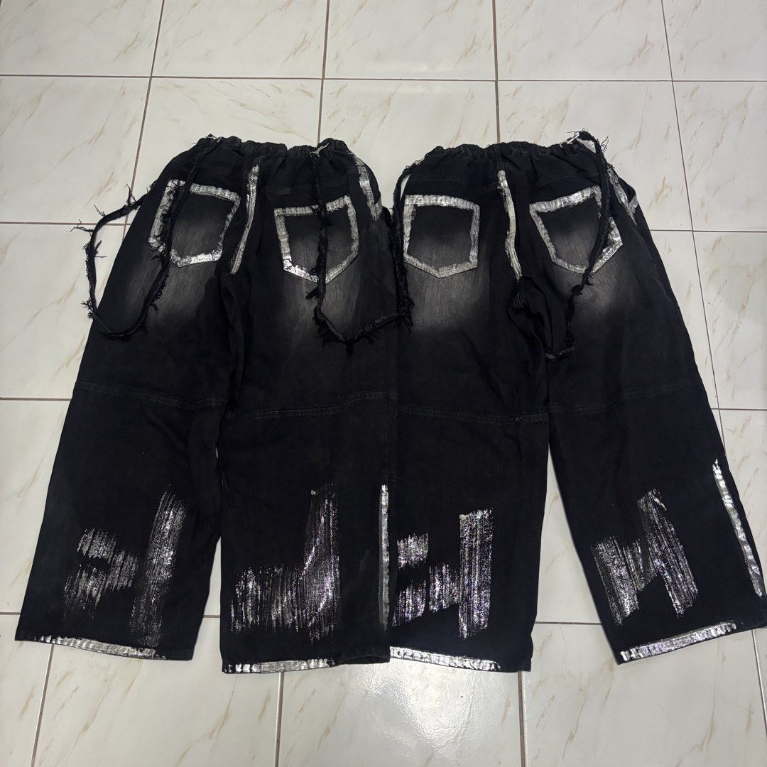 Adrer japanese pants (Category: Jeans) located in San Fernando. Submitted by diff.thr1ft (Listing ID 1468115366, Image 2). Description: - Brand: Adrer - Color: Black with silver metallic/foil distressed print details - Style: Japanese streetwear, wide-leg fit - Features: Elastic high waist, distressed raw edges, side straps with metal hardware, branded button - Condition: Brand new with tags (BNWT) - Perfect for daily casual wear or edgy streetwe