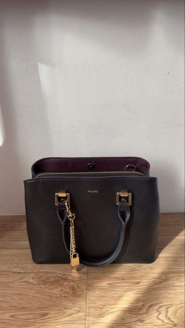 Aldo Black and Maroon Structured Tote Handbag (Category: Tote Bags) located in Lipa City. Submitted by eden.cheexe (Listing ID 1468283036, Image 1). Description: - Brand: Aldo - Color: Classic black exterior with a stylish maroon interior - Hardware: Gold-tone accents and front logo branding - Extras: Removable gold padlock and chain charm included - Compartments: Center zipped compartment with open sections and magnetic closure - Organization: M