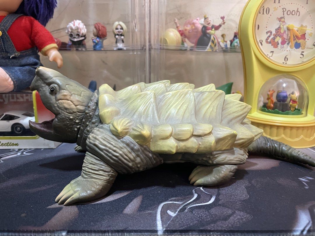 Alligator Snapping Turtle Toy Action Figure (Category: Figurines & Statues) located in Agdangan. Submitted by kuradekawaii_06 (Listing ID 1468095993, Image 2). Description: - Detailed alligator snapping turtle action figure - Features a greenish-brown scaly body and a sharp, spiky shell - Wide open mouth showing a realistic reddish tongue - Textured claws and posable tail and limbs - Stamped Sunplaza on the bottom of one foot - Perfect collectibl