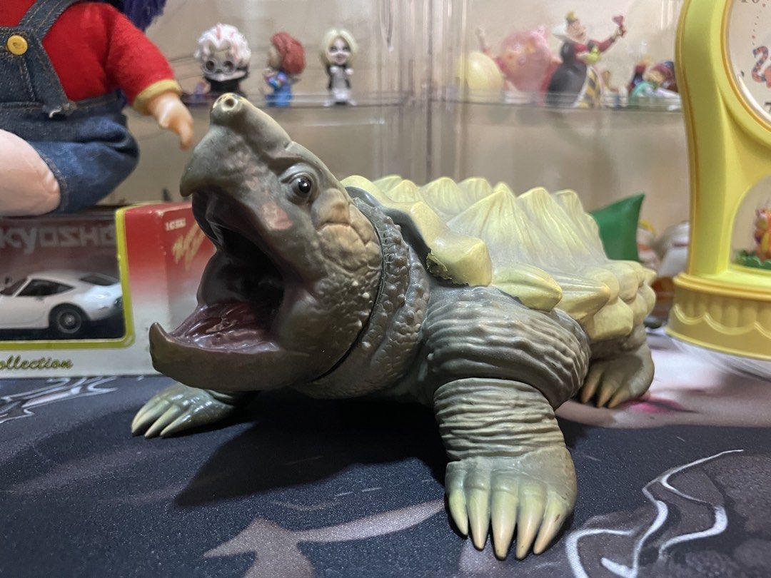 Alligator Snapping Turtle Toy Action Figure (Category: Figurines & Statues) located in Agdangan. Submitted by kuradekawaii_06 (Listing ID 1468095993, Image 1). Description: - Detailed alligator snapping turtle action figure - Features a greenish-brown scaly body and a sharp, spiky shell - Wide open mouth showing a realistic reddish tongue - Textured claws and posable tail and limbs - Stamped Sunplaza on the bottom of one foot - Perfect collectibl