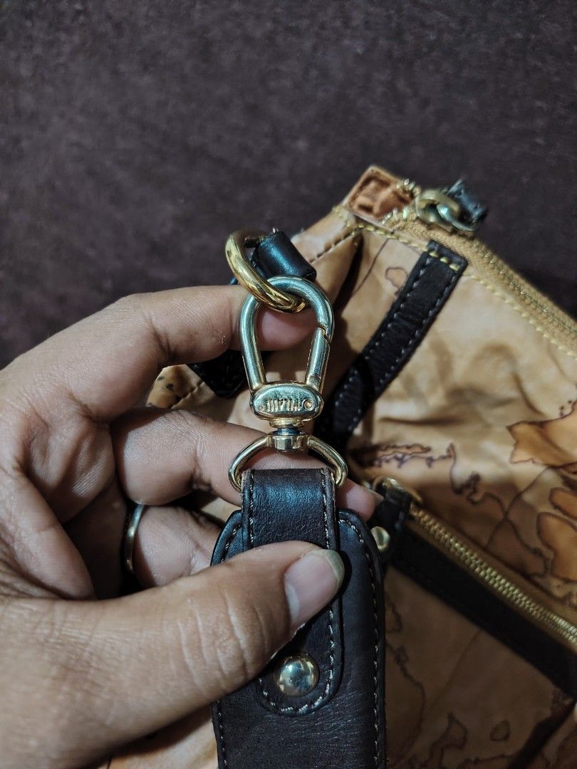 Alviero Martini Map Print Handbag (Category: Luxury Bags & Wallets) located in Nasipit. Submitted by chillprot51456 (Listing ID 1468229415, Image 2). Description: Alviero Martini handbag with distinctive world map print all over. Dark brown leather trim and gold tone hardware. Zippered top closure with extra zippered pocket on the front. Inside fabric lining features Alviero Martini branding. Includes strap hardware. Has noticeable seam tearing a
