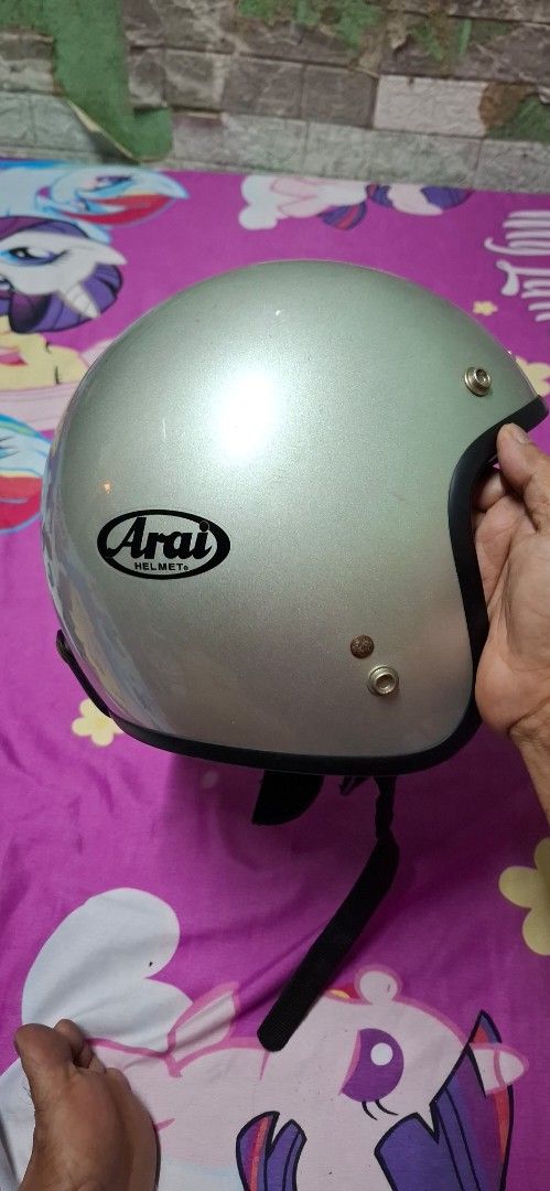 Arai Helmet Silver Open Face (Category: Caps & Hats) located in Quezon City. Submitted by robertlimbao (Listing ID 1468138134, Image 2). Description: - Brand: Arai - Type: Open face helmet - Color: Silver with black lining and chin strap - Features: Metal snap buttons along the top edge - Condition: Minor scratches and slight wear marks on the outer shell - Authentic and ready to use.