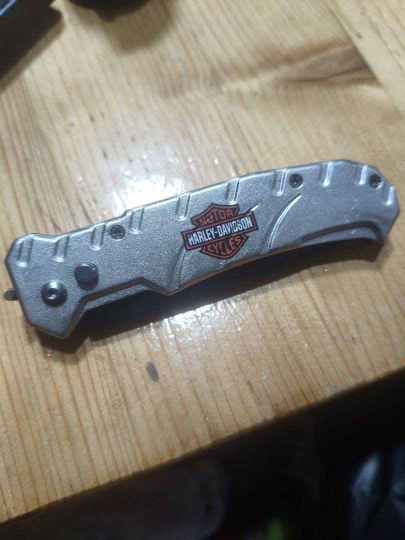 Armed Force Tactical Harley-Davidson 162HDSL Folding Knife (Category: Hiking & Camping) located in Baguio. Submitted by baguiobeans (Listing ID 1468184010, Image 2). Description: - Model: Armed Force Tactical 162HDSL with Harley-Davidson branding - Blade: Black 440C stainless steel, partially serrated - Handle: Silver finish with branded design - Features: Built-in back pocket clip for easy carry - Inclusion: Comes with the original black box - C