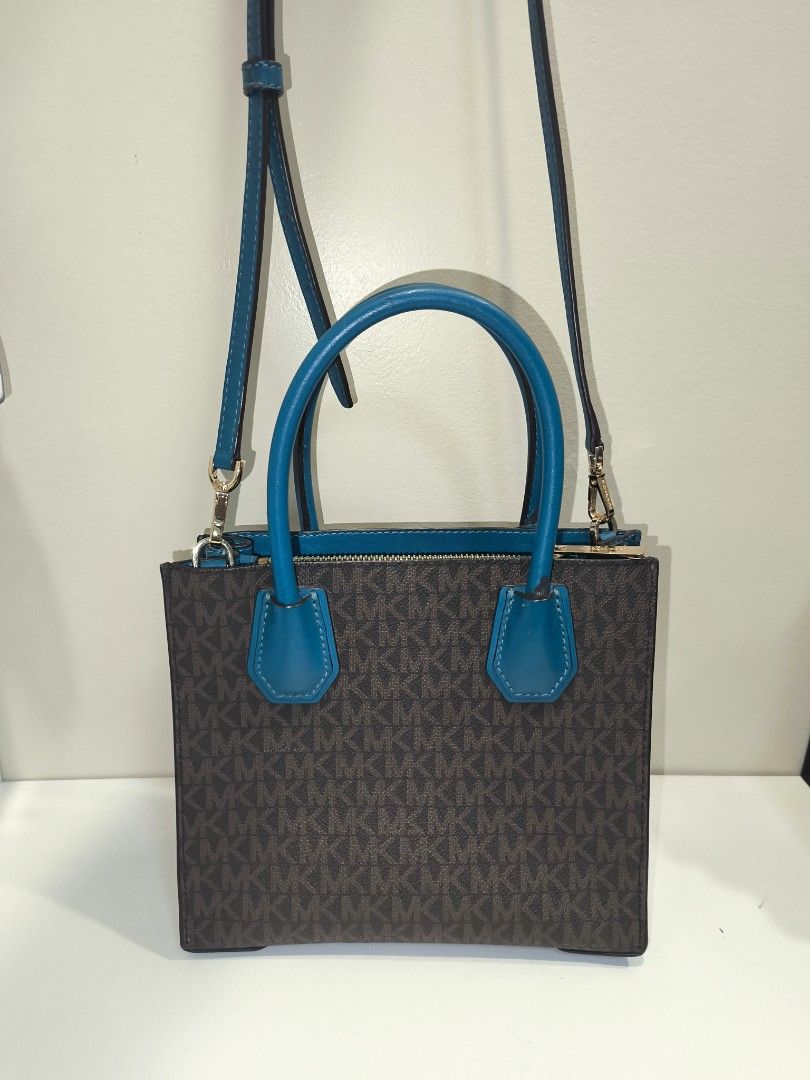 AUTH MICHAEL KORS MED CONVERTIBLE TOTE BAG (Category: Shoulder Bags) located in Baguio. Submitted by zia_zab (Listing ID 1468068678, Image 3). Description: Michael Kors Mercer Small Convertible Tote features a brown monogram pattern with teal accents. It has a top handle and a detachable shoulder strap. The interior has a zippered pocket and a small slip pocket. The bag has a gold-tone MK logo charm. The interior lining is teal. Slightly used, so