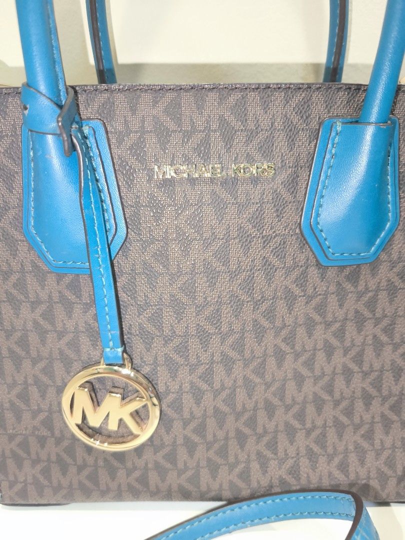 AUTH MICHAEL KORS MED CONVERTIBLE TOTE BAG (Category: Shoulder Bags) located in Baguio. Submitted by zia_zab (Listing ID 1468068678, Image 2). Description: Michael Kors Mercer Small Convertible Tote features a brown monogram pattern with teal accents. It has a top handle and a detachable shoulder strap. The interior has a zippered pocket and a small slip pocket. The bag has a gold-tone MK logo charm. The interior lining is teal. Slightly used, so