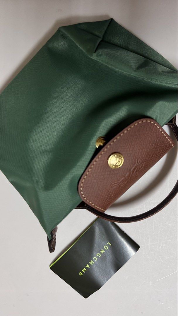 Authentic Longchamp Green Nylon Mini Pouch Bag (Category: Luxury Bags & Wallets) located in Manila. Submitted by fcloset24 (Listing ID 1468090210, Image 3). Description: - Color: Green nylon with brown leather flap and handles - Hardware: Gold-tone snap button with jockey logo - Style: Compact folded design - Inclusions: Comes with original brand card - Condition: Clean fabric and sturdy trim.