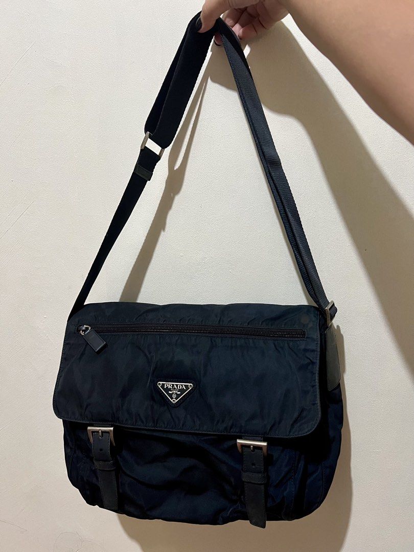 Authentic Prada Black Nylon Messenger Bag (Category: Luxury Bags & Wallets) located in Dagupan City. Submitted by casadebayongph (Listing ID 1468221891, Image 2). Description: Prada messenger bag in black nylon. Flap front design with silver tone buckles and iconic triangle logo badge. Zip pocket right on the front flap. Adjustable canvas shoulder strap for easy daily carry. Clean silhouette that works for both guys and girls. Great everyday piec