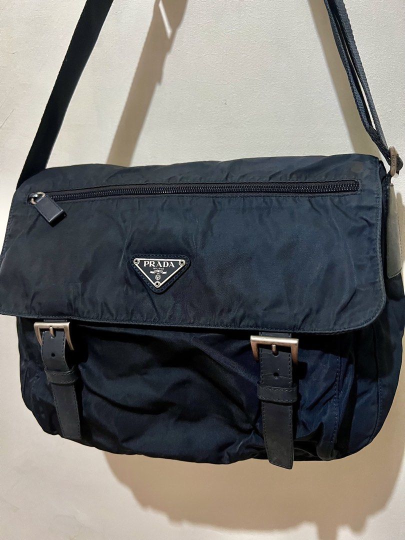 Authentic Prada Black Nylon Messenger Bag (Category: Luxury Bags & Wallets) located in Dagupan City. Submitted by casadebayongph (Listing ID 1468221891, Image 3). Description: Prada messenger bag in black nylon. Flap front design with silver tone buckles and iconic triangle logo badge. Zip pocket right on the front flap. Adjustable canvas shoulder strap for easy daily carry. Clean silhouette that works for both guys and girls. Great everyday piec