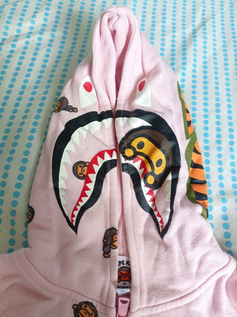 BAPE kidz Milo Monogram (Category: Babies & Kids Fashion) located in Manila. Submitted by ogiefernandez (Listing ID 1468083957, Image 2). Description: - 100% Authentic BAPE Kids pink full-zip hoodie - Iconic all-over Baby Milo graphic print - Classic shark face hood with contrast teeth, eyes, and tiger stripe back detail - Branded pink zipper hardware with woven neck and gold sleeve tags - Cozy soft fleece lining and convenient front zip pockets.