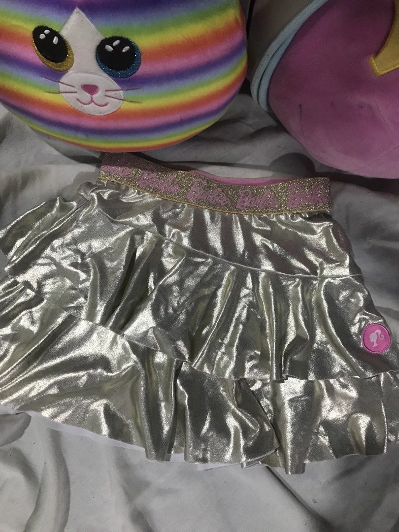 Barbie Metallic Silver Ruffled Skirt Size 2 (Category: Babies & Kids Fashion) located in Caloocan City. Submitted by julie_shooooopppp (Listing ID 1468211800, Image 1). Description: - Brand: Barbie - Color/Style: Metallic silver tiered ruffle skirt with fun shiny fabric - Size: Size 2 (Fits height 92cm, waist 54cm) - Waistband: Comfy elastic with gold glitter and pink Barbie branding - Details: Features a pink Barbie silhouette logo patch near th