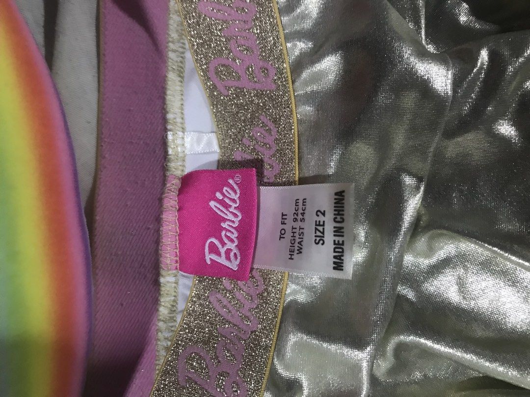 Barbie Metallic Silver Ruffled Skirt Size 2 (Category: Babies & Kids Fashion) located in Caloocan City. Submitted by julie_shooooopppp (Listing ID 1468211800, Image 2). Description: - Brand: Barbie - Color/Style: Metallic silver tiered ruffle skirt with fun shiny fabric - Size: Size 2 (Fits height 92cm, waist 54cm) - Waistband: Comfy elastic with gold glitter and pink Barbie branding - Details: Features a pink Barbie silhouette logo patch near th