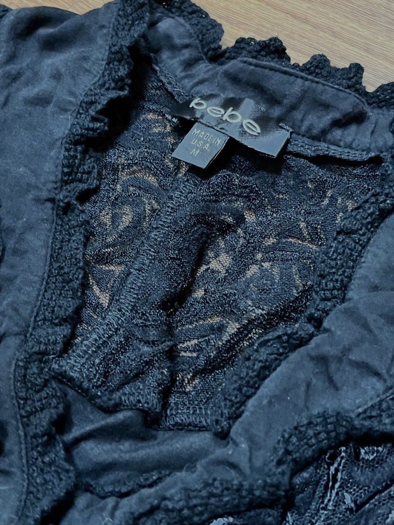 Authentic bebe Black Lace Button-Up Blouse (Category: Blouses) located in Manila. Submitted by wishful_willow (Listing ID 1468151233, Image 2). Description: PRICE IS NEGOTIABLE ₱450 - Brand: bebe - Size: M (Made in USA) - Color: Classic Black - Material: Soft and comfortable fabric blend - Details: Stunning lace paneling on front yoke and upper back - Design: Fabric-covered front buttons with charming ruffled trim - Sleeves: Quarter-length with s