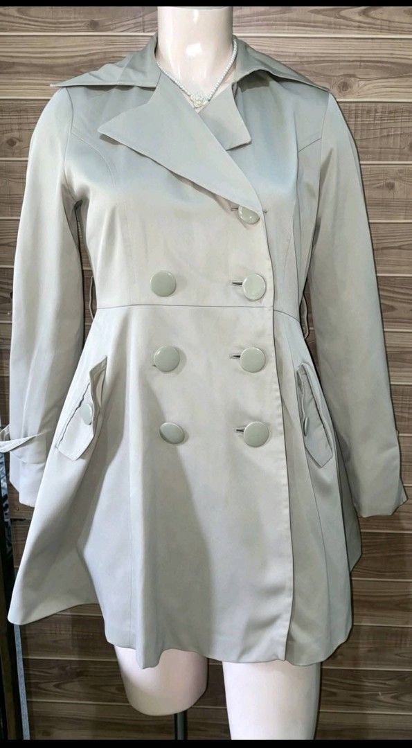Beige double-breasted flared trench coat jacket (Category: Coats, Jackets and Outerwear) located in Santa Rosa. Submitted by happystorm.c97c56 (Listing ID 1468147052, Image 1). Description: - Color: Classic Neutral Beige - Design: Double-breasted button front with a chic flare skirt shape from the waist down - Collar: Large neckline with structured lapels - Sleeves: Long sleeves featuring stylish strap details at the cuffs - Pockets: Two practica
