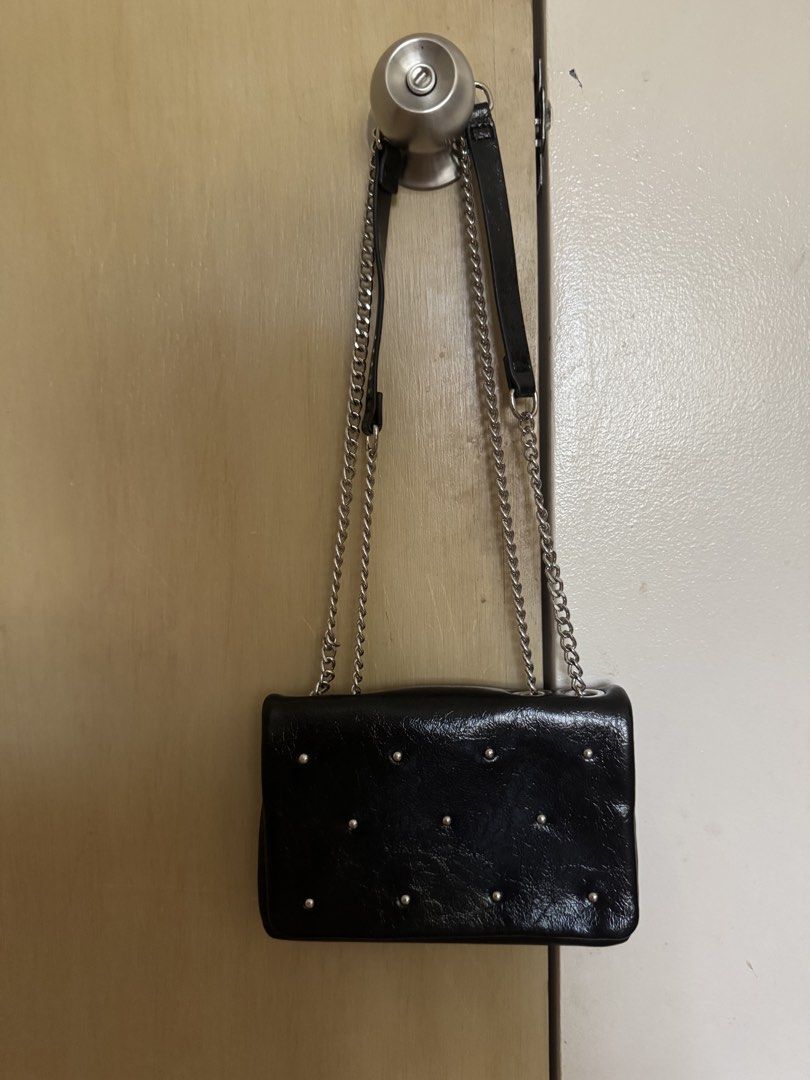 Black Studded Shoulder Bag with Chain Strap (Category: Cross-body Bags) located in Muntinlupa City. Submitted by francesca14 (Listing ID 1468077021, Image 1). Description: - Style: Black crinkled patent finish shoulder bag with silver-tone front studs - Closure: Secure magnetic snap closure - Strap: Double chain and faux leather strap - Interior: Multiple compartments with a slip pocket and clean lining with tag attached - Versatility: Great size