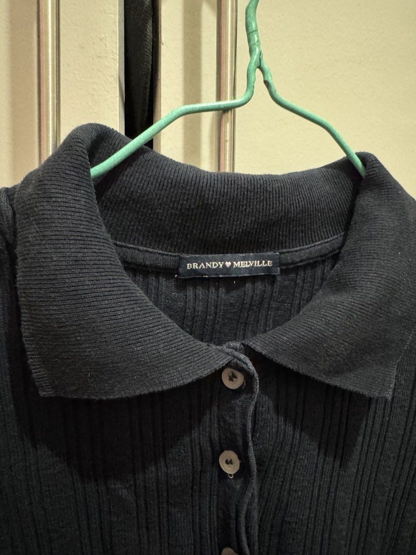 Brandy Melville Black Ribbed Polo Top (Category: Shirts) located in Rosales. Submitted by thriftingismygame (Listing ID 1468170270, Image 3). Description: - Brand: Brandy Melville - Color: Black - Style: Short sleeve ribbed polo shirt with button-up front and classic collar - Fit: Fitted cut - Versatile basic piece, easy to style with jeans or skirts.