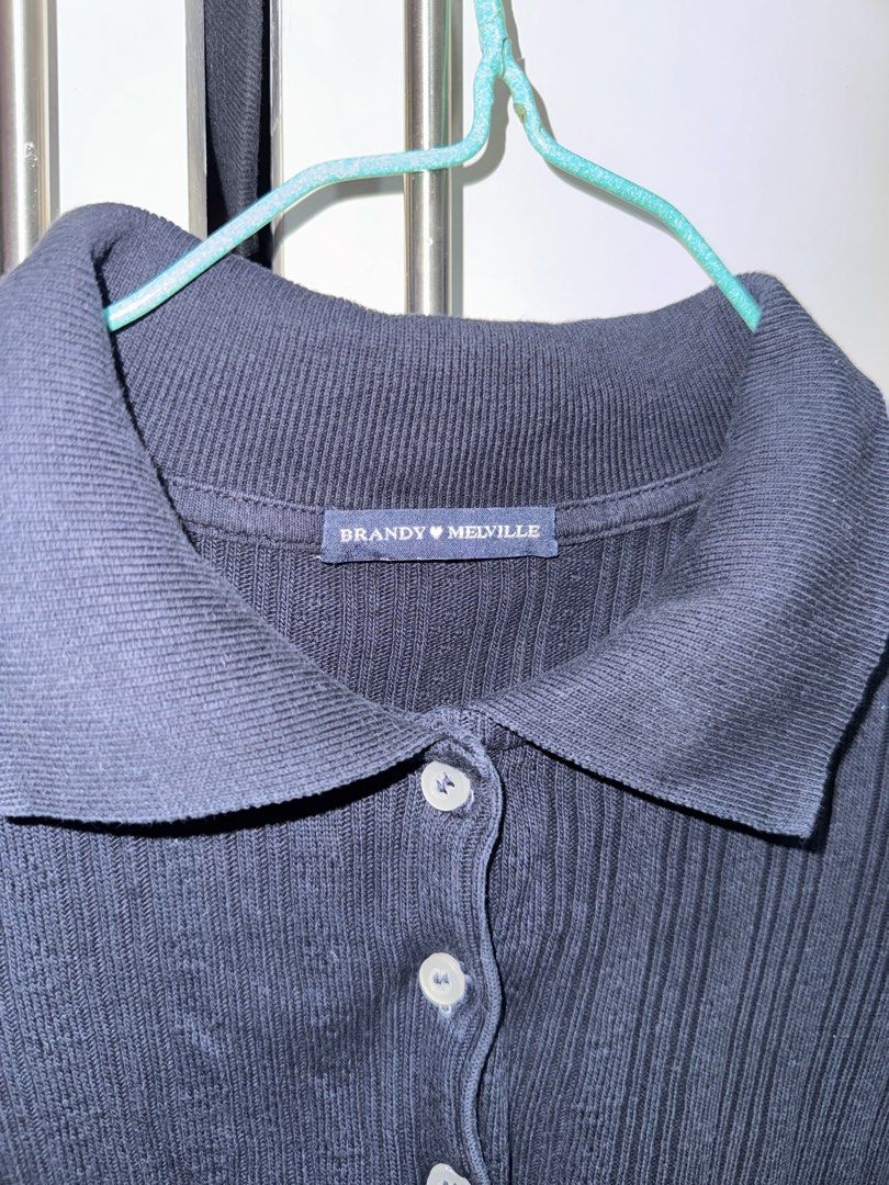 Brandy Melville Black Ribbed Polo Top (Category: Shirts) located in Rosales. Submitted by thriftingismygame (Listing ID 1468170270, Image 2). Description: - Brand: Brandy Melville - Color: Black - Style: Short sleeve ribbed polo shirt with button-up front and classic collar - Fit: Fitted cut - Versatile basic piece, easy to style with jeans or skirts.