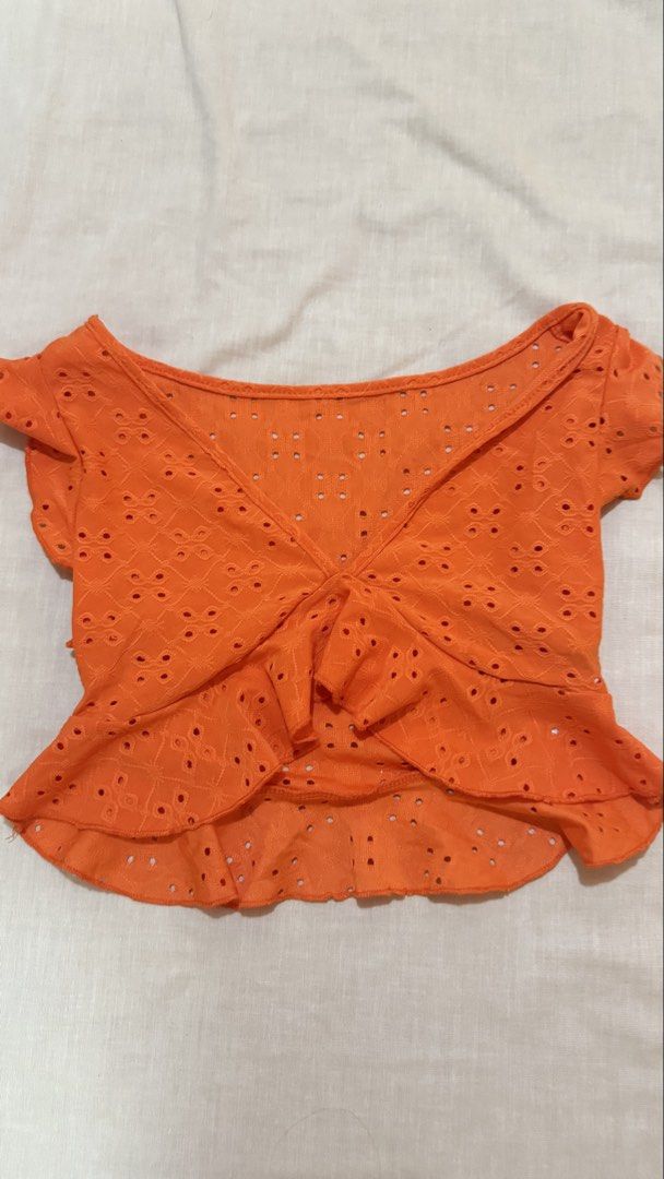 Bright Orange Eyelet Embroidered Ruffle Crop Top (Category: Sleeveless) located in Makati City. Submitted by jianciee (Listing ID 1468151148, Image 1). Description: - Color: Bright orange - Material: Lightweight fabric with all-over floral-shaped eyelet cutouts - Design: Short flutter sleeves, open wrap-style crossover front, and double ruffled hem - Fit: Crop top length, perfect for summer - Styling: Easy to match with high-waisted denim shorts 