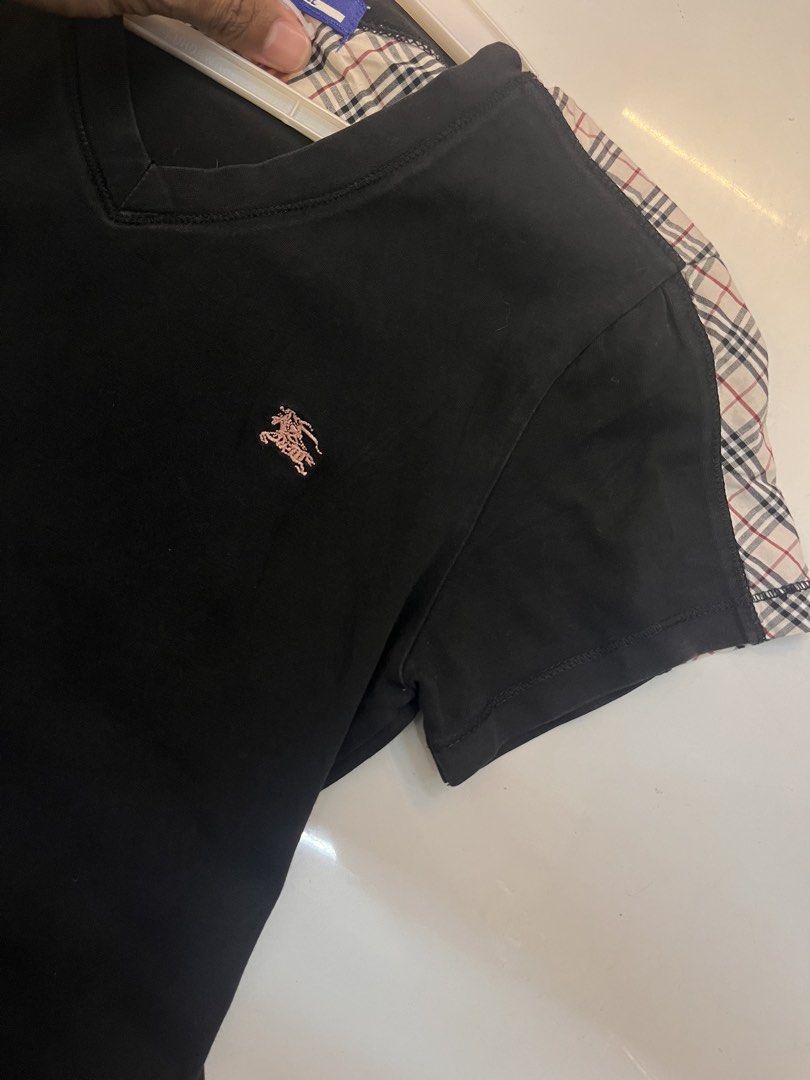 Burberry Blue Label Black V-Neck Tee with Nova Check Shoulders (Category: Shirts) located in Dagupan City. Submitted by shanadongsb (Listing ID 1468090865, Image 3). Description: - Brand: Burberry Blue Label - Color: Black with signature nova check shoulders and collar lining - Details: Embroidered pinkish equestrian knight logo on chest, blue brand label - Fit: V-neck, short sleeves - Material: Lightweight, breathable cotton - Condition: Excelle