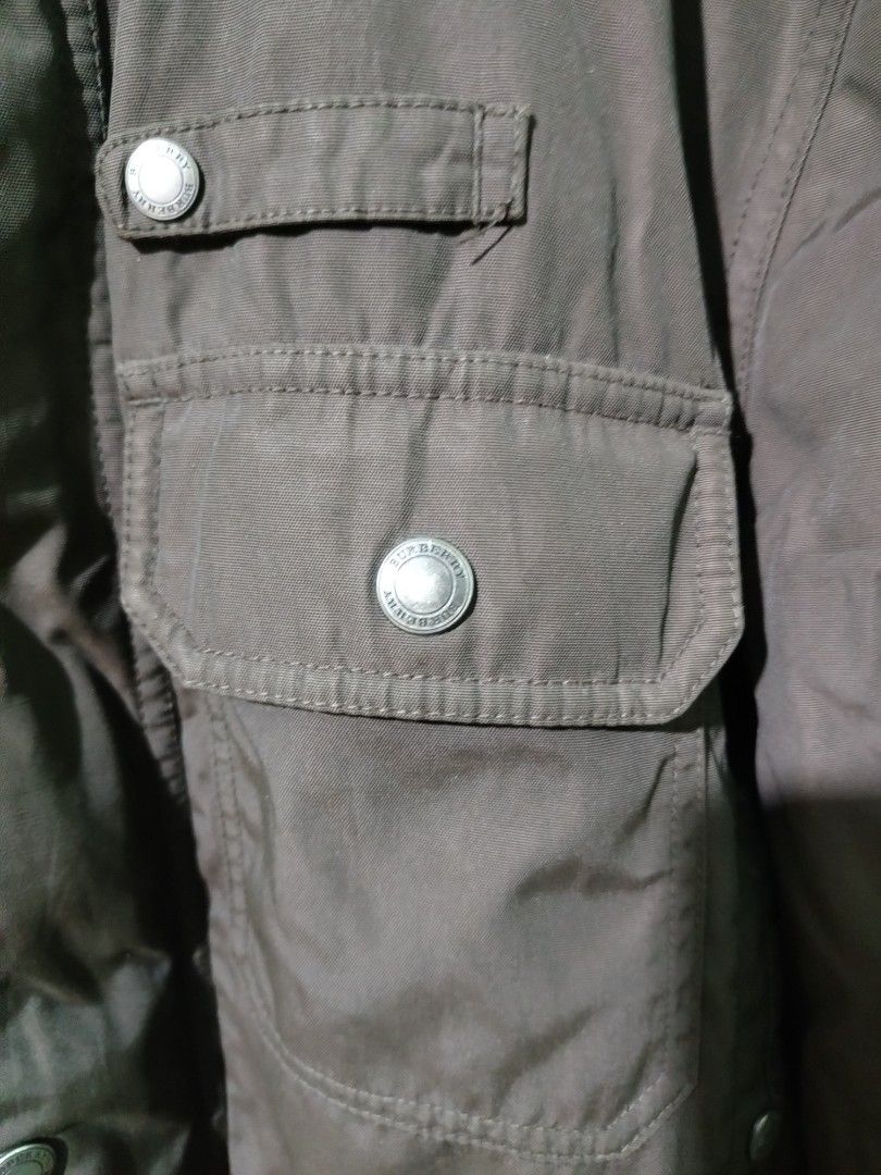 Burberry London Brown Quilted Check Jacket (Category: Coats, Jackets and Outerwear) located in Lucena. Submitted by thrifteditem (Listing ID 1468236973, Image 2). Description: Burberry London brown utility jacket with iconic check lining inside. Multiple front pockets, snap buttons, zip closure with YKK hardware. Stand collar with buckle strap detail. Classic winter outerwear piece in earthy tones..