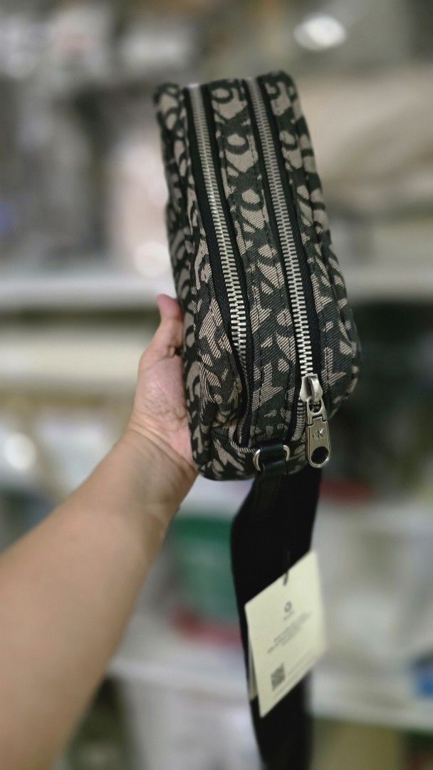 Calvin Klein Monogram Crossbody Bag (Category: Cross-body Bags) located in Quezon City. Submitted by momof3_11 (Listing ID 1468231993, Image 3). Description: - Brand: Calvin Klein - Condition: Brand new with tags attached - Design: Dark monogram print pattern with black leather bottom base for structure - Closure & Hardware: Secure double zip closure with sleek silver hardware - Strap: Adjustable black shoulder strap (still wrapped in protective 